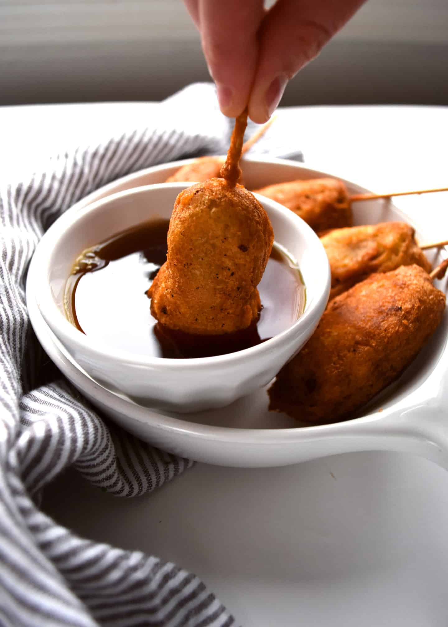 sausage and pancake on a stick, breakfast corn dogs with a bowl of syrup for dipping