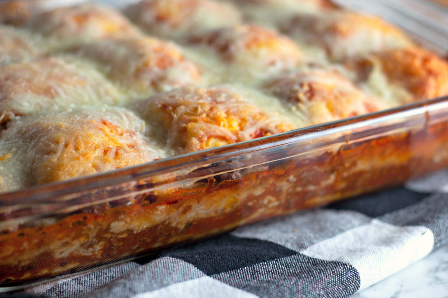 A pan with layers of hot sauce, cheese, and ravioli baked up.