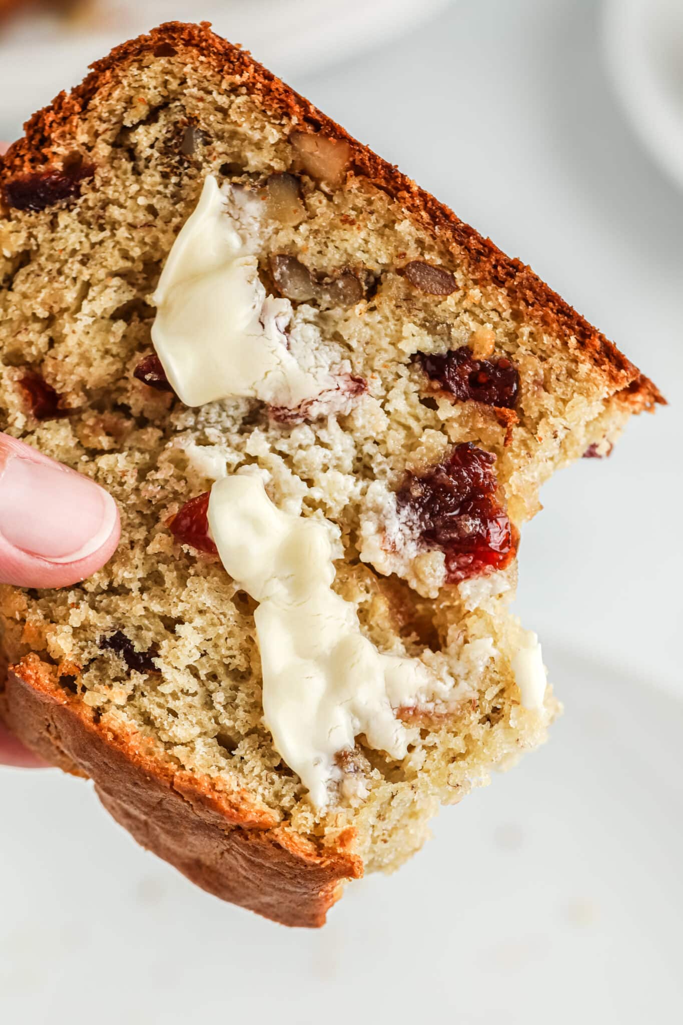 banana bread with cranberries, walnuts, and butter on top.