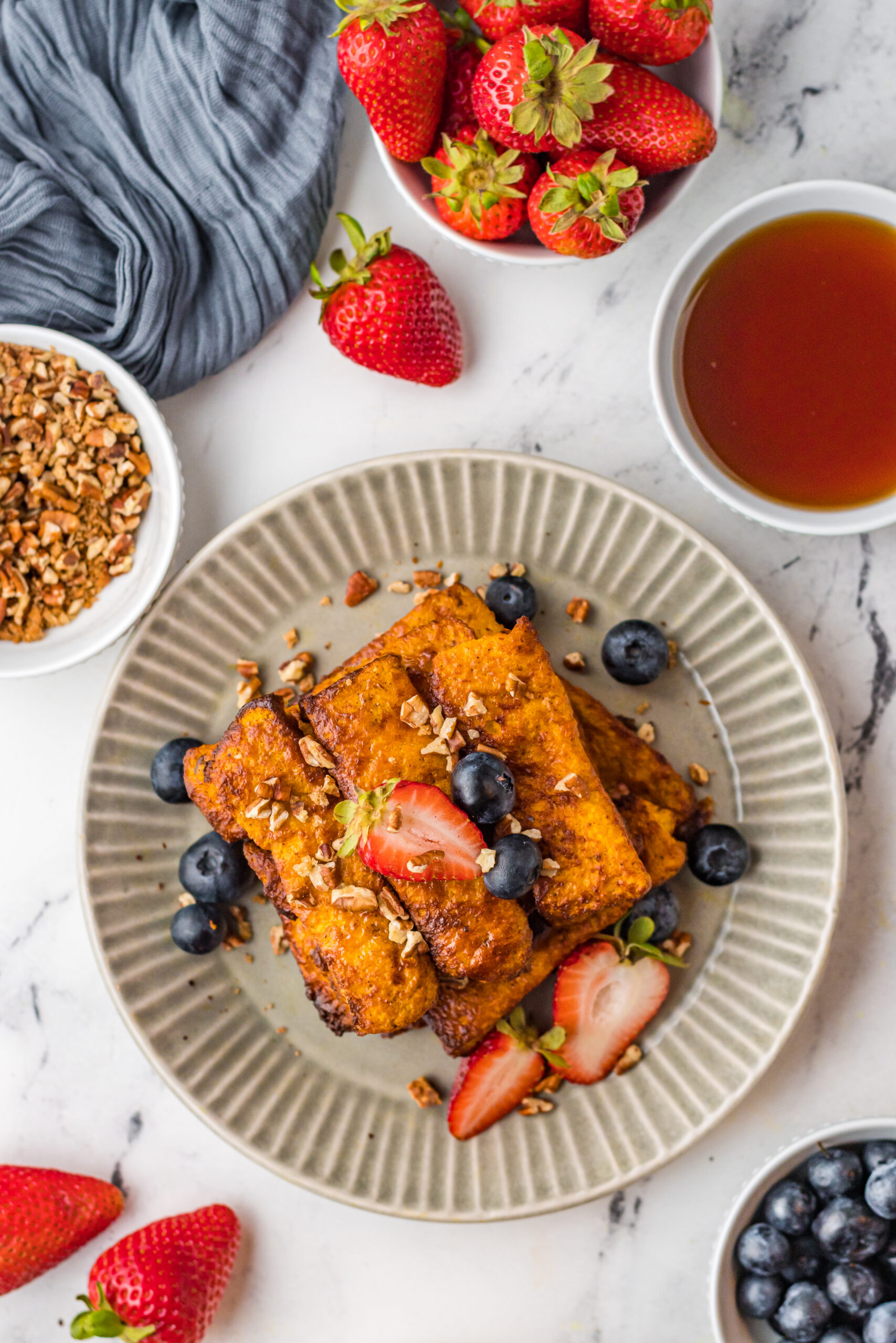 A plate of french toast sticks with fresh fruit. 