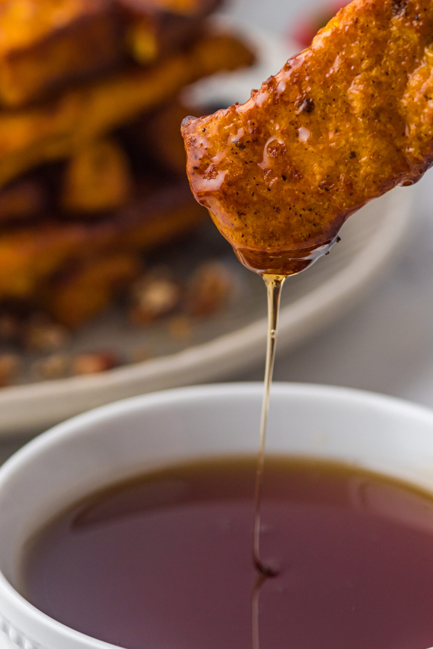 French Toast Stick being dipped in syrup