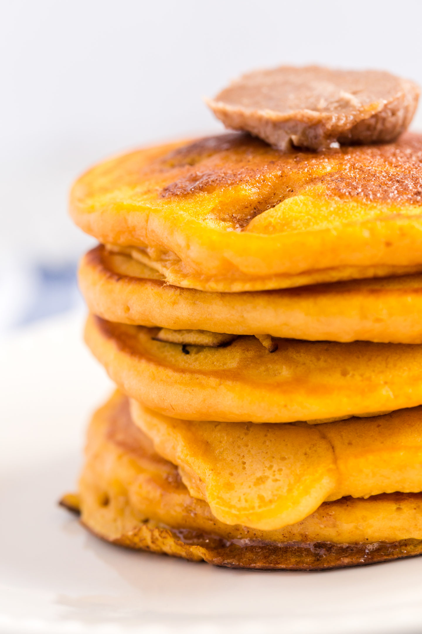 stack of fluffy and hearty pumpkin pancakes topped with cinnamon butter