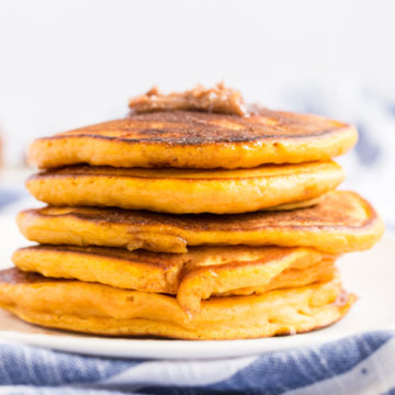 A stack of pumpkin pancakes with a dollup of cinnamon butter on the top.