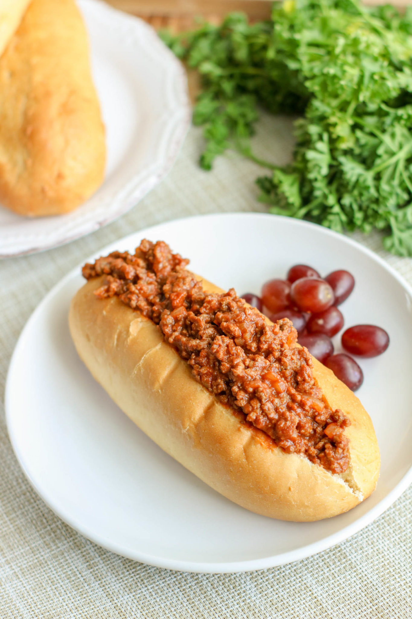 The finished sloppy joes in a bun, on a plate.