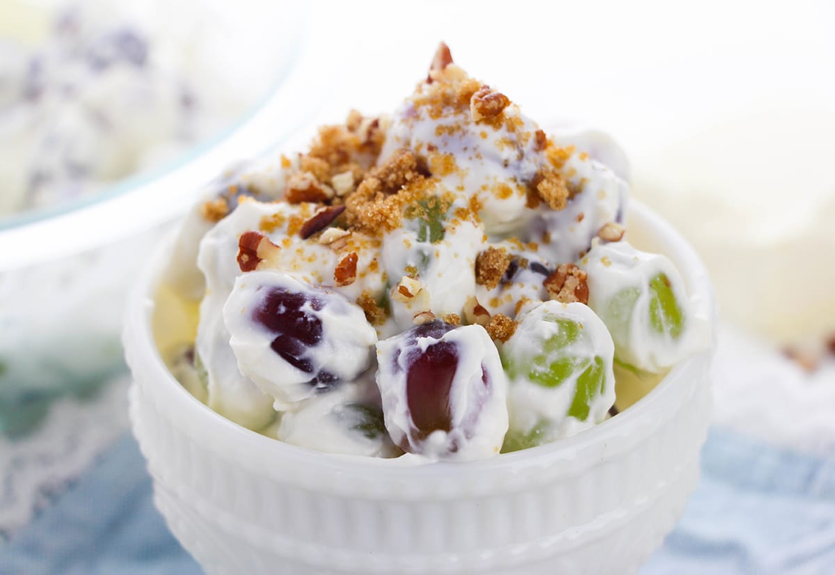 A dish of creamy grape salad with brown sugar and chopped nuts on top.